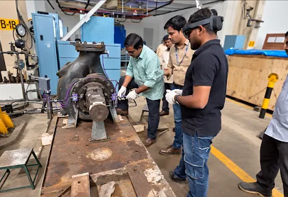 Engineers inspecting an industrial pump on the shop floor, one wearing a mixed-reality headset
